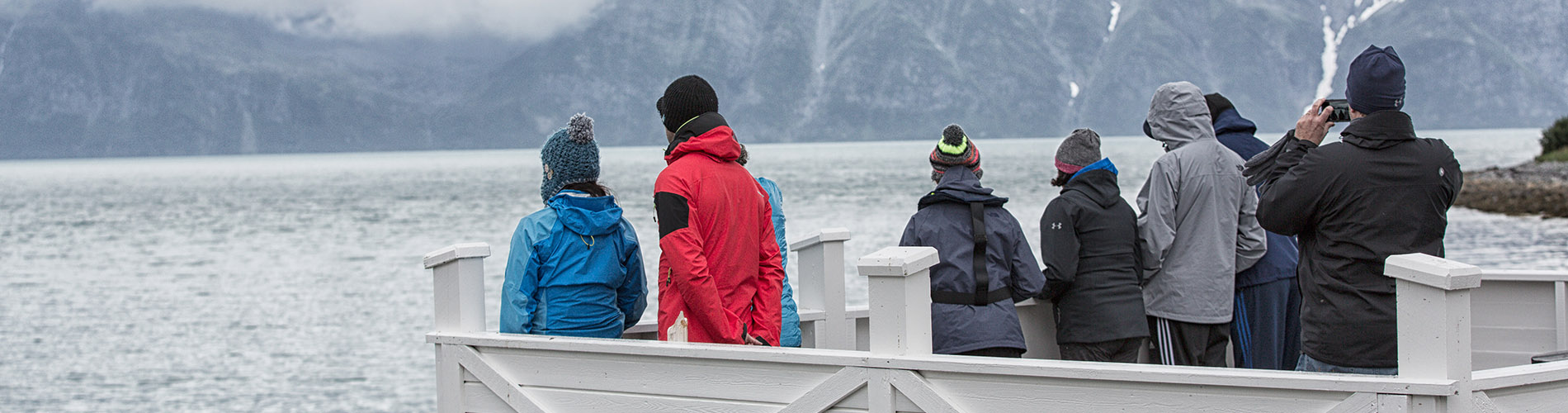 Menschen am Steg und schauen auf Fjord